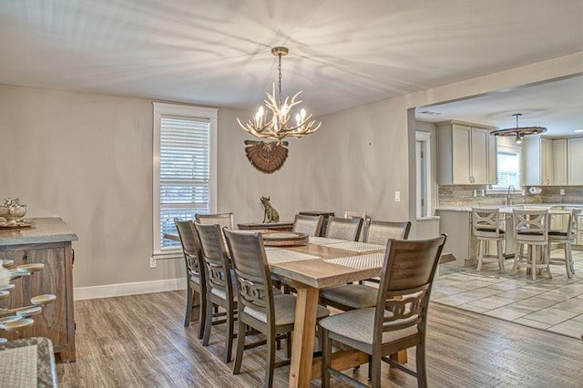 dining room with light wood-type flooring, an inviting chandelier, plenty of natural light, and sink