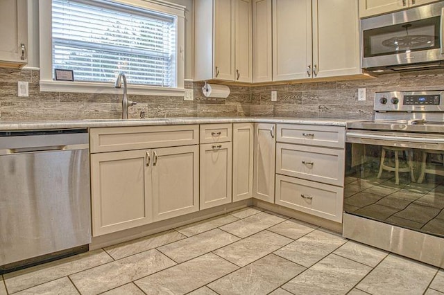 kitchen featuring backsplash, light stone counters, sink, and stainless steel appliances