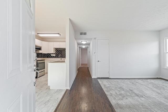 kitchen with sink, appliances with stainless steel finishes, white cabinets, hardwood / wood-style flooring, and backsplash