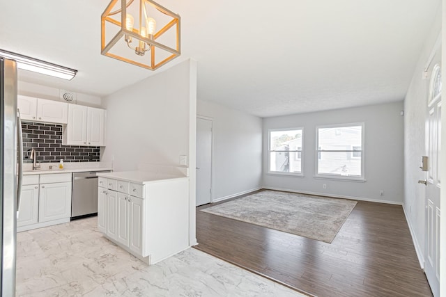 kitchen with sink, white cabinetry, tasteful backsplash, hanging light fixtures, and stainless steel appliances