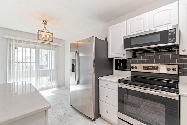 kitchen with pendant lighting, decorative backsplash, white cabinets, and appliances with stainless steel finishes