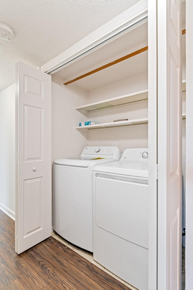 washroom with dark hardwood / wood-style floors, washer and clothes dryer, and a textured ceiling