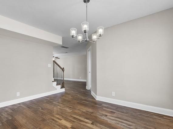 spare room featuring dark hardwood / wood-style floors and a chandelier