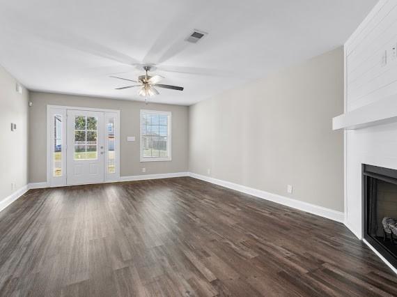 unfurnished living room with dark hardwood / wood-style floors and ceiling fan