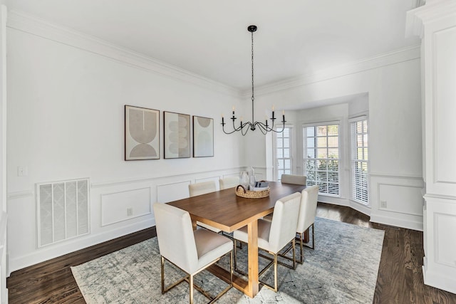 dining room with crown molding, dark hardwood / wood-style flooring, and an inviting chandelier