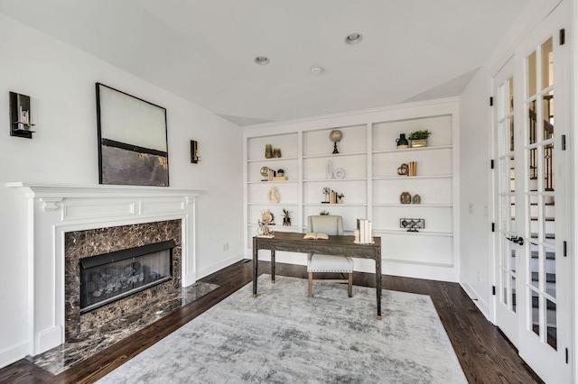 home office featuring dark hardwood / wood-style floors, built in features, and a fireplace