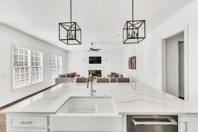 kitchen featuring decorative light fixtures, white cabinetry, crown molding, and sink