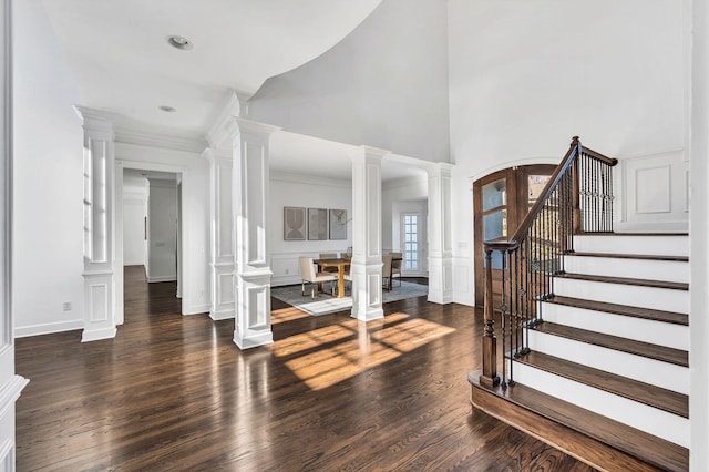 entryway with a high ceiling, dark hardwood / wood-style floors, decorative columns, and ornamental molding