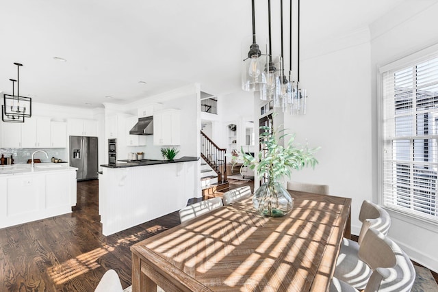 dining room with sink, ornamental molding, dark wood-type flooring, and an inviting chandelier