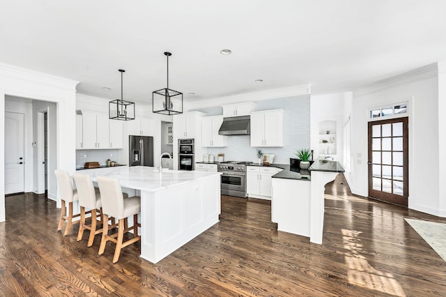 kitchen with pendant lighting, a center island with sink, high quality appliances, dark hardwood / wood-style floors, and white cabinetry