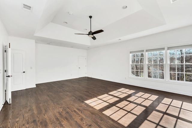 spare room with dark hardwood / wood-style floors, ceiling fan, and a tray ceiling