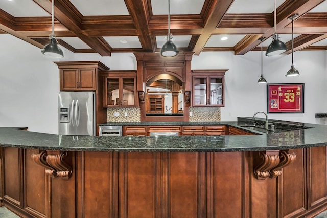 kitchen featuring decorative backsplash, stainless steel fridge, hanging light fixtures, and dark stone counters