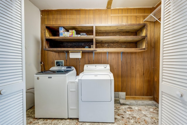 laundry room with washer and dryer and wood walls