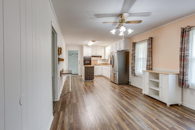 kitchen featuring stainless steel refrigerator with ice dispenser, dark hardwood / wood-style flooring, ceiling fan, crown molding, and white cabinetry