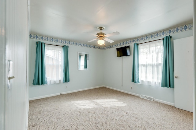 empty room with ceiling fan and light carpet