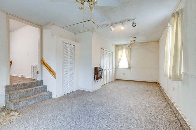 empty room featuring ceiling fan, light colored carpet, rail lighting, and heating unit