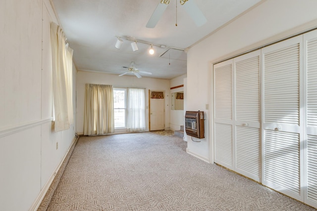 unfurnished living room with track lighting, ceiling fan, light colored carpet, and heating unit