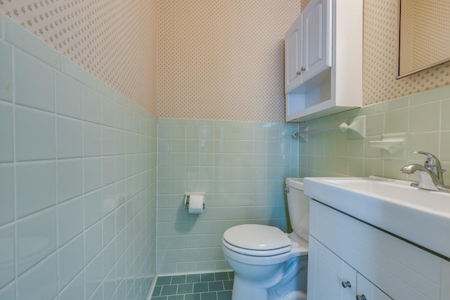 bathroom featuring vanity, tile walls, and toilet