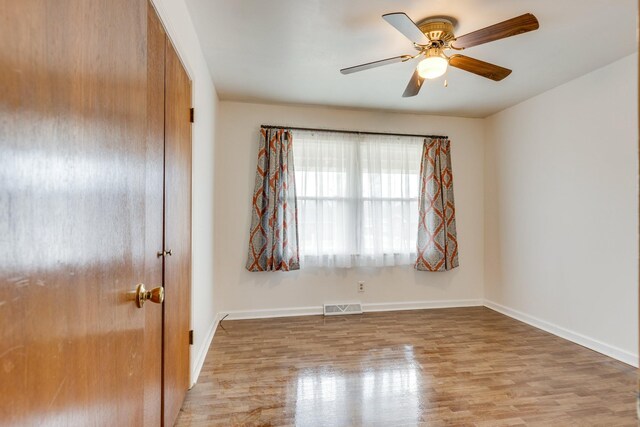 empty room with ceiling fan and light hardwood / wood-style flooring