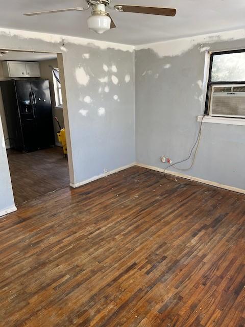 unfurnished room with dark wood-style flooring, cooling unit, a ceiling fan, and baseboards