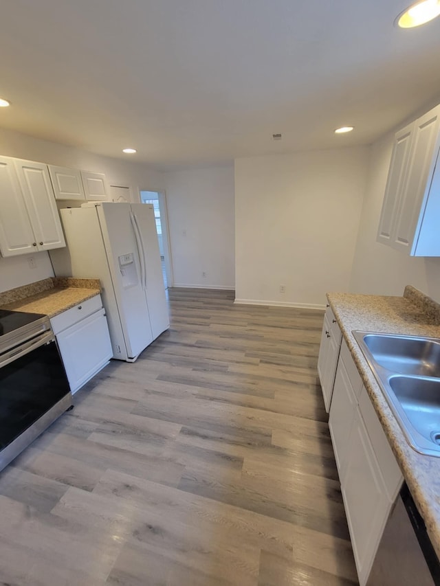 kitchen with white refrigerator with ice dispenser, sink, stainless steel stove, light hardwood / wood-style flooring, and white cabinetry