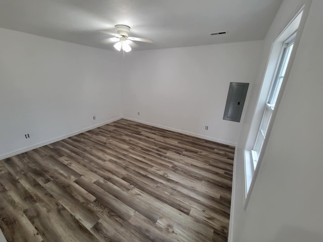 empty room with dark hardwood / wood-style floors, ceiling fan, and electric panel