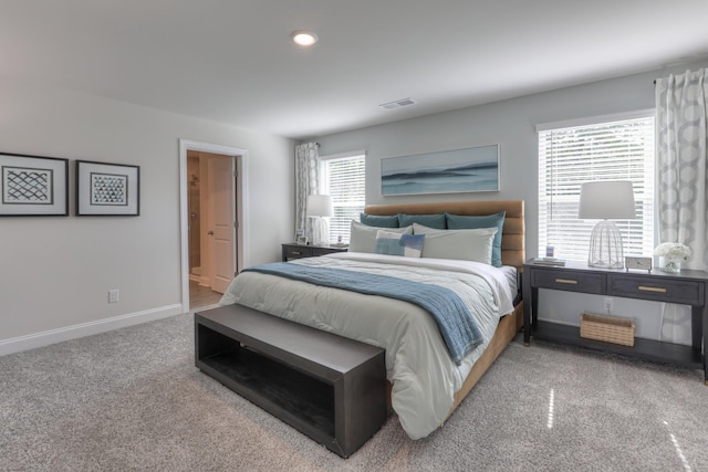 bedroom with ensuite bathroom and carpet floors