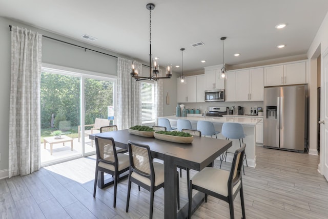 dining area with light hardwood / wood-style flooring and a notable chandelier