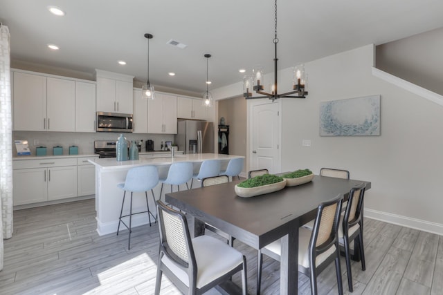 dining room featuring sink, light hardwood / wood-style flooring, and a notable chandelier