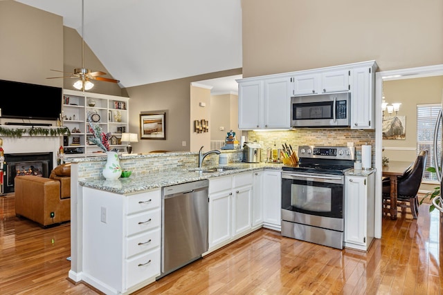 kitchen featuring white cabinets, appliances with stainless steel finishes, high vaulted ceiling, and sink