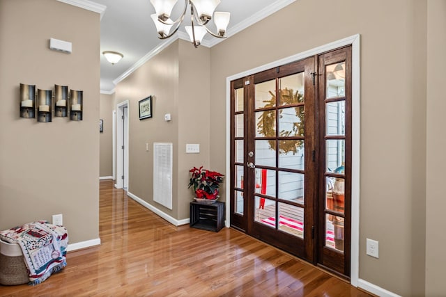 foyer entrance with a chandelier, wood-type flooring, and ornamental molding