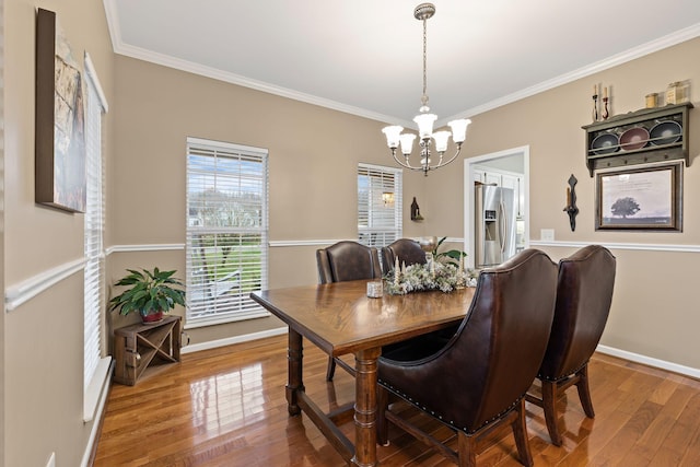 dining area with hardwood / wood-style flooring, crown molding, and a chandelier