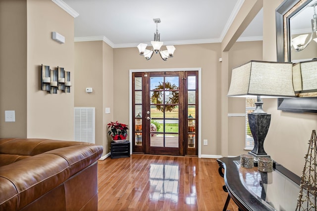 foyer with hardwood / wood-style floors, crown molding, and an inviting chandelier