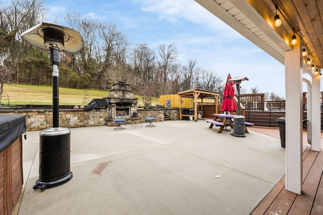 view of patio featuring an outdoor stone fireplace and a hot tub