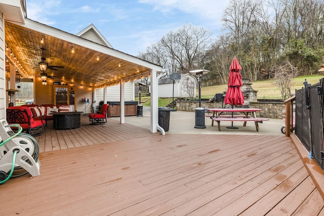 deck featuring an outdoor living space, a hot tub, and a storage shed