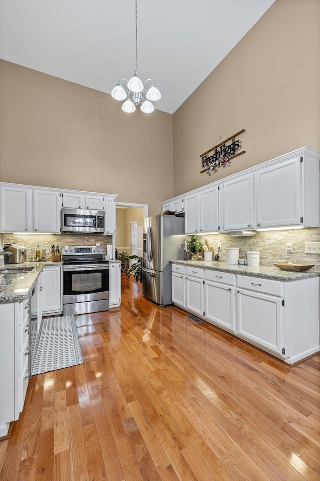 kitchen featuring white cabinets, stainless steel appliances, and a high ceiling