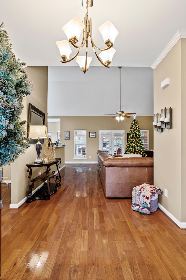 living room with french doors, a high ceiling, wood-type flooring, ceiling fan with notable chandelier, and ornamental molding