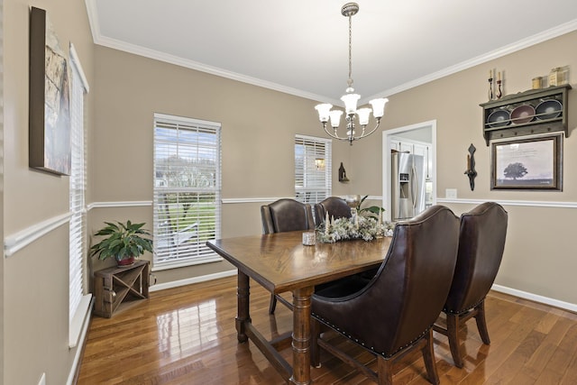 dining area with a notable chandelier, baseboards, ornamental molding, and wood finished floors