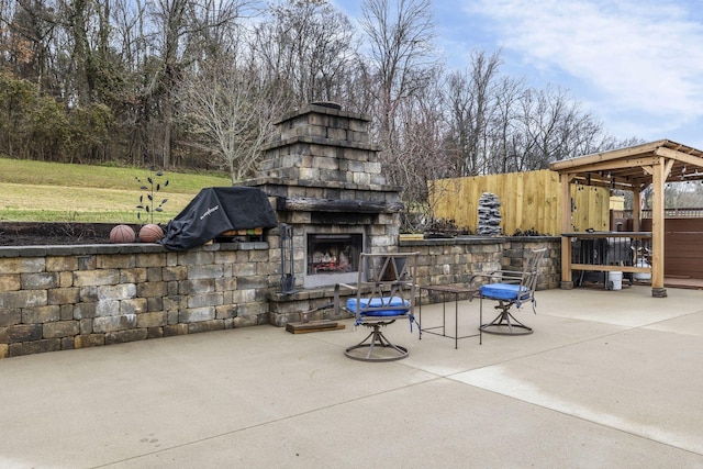 view of patio featuring an outdoor stone fireplace and fence