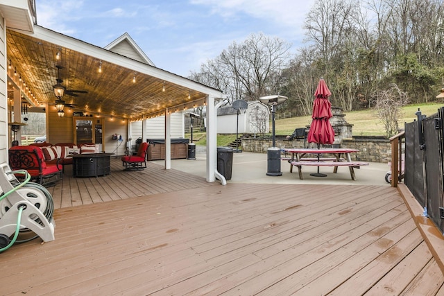 wooden deck with outdoor dining space, an outdoor fire pit, and a hot tub