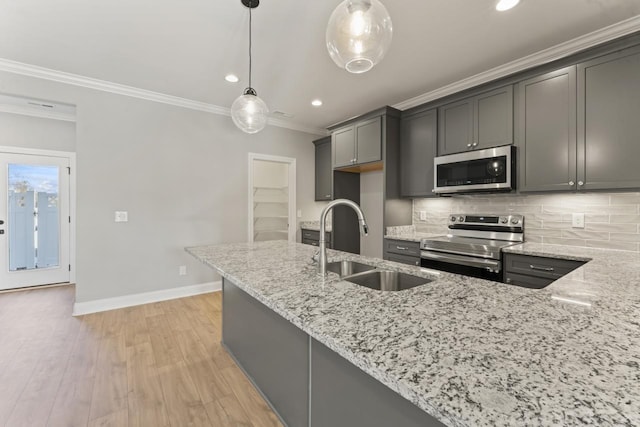kitchen featuring light wood-type flooring, light stone counters, stainless steel appliances, sink, and hanging light fixtures