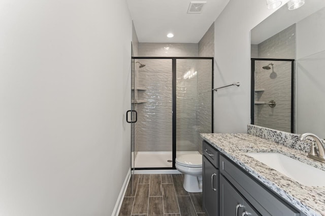 bathroom featuring vanity, an enclosed shower, and toilet