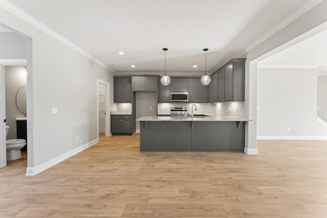 kitchen with gray cabinetry, hanging light fixtures, light hardwood / wood-style flooring, decorative backsplash, and appliances with stainless steel finishes