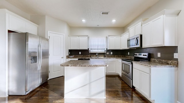 kitchen featuring white cabinetry, a center island, dark wood-type flooring, and appliances with stainless steel finishes