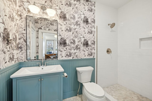 bathroom with vanity, toilet, and a tile shower