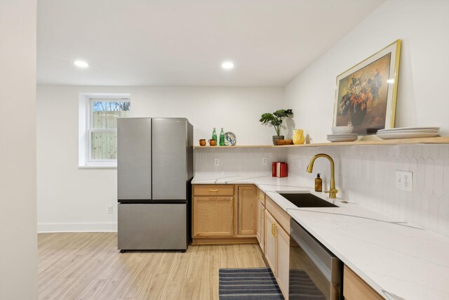 kitchen with dishwashing machine, sink, stainless steel fridge, light wood-type flooring, and light brown cabinets