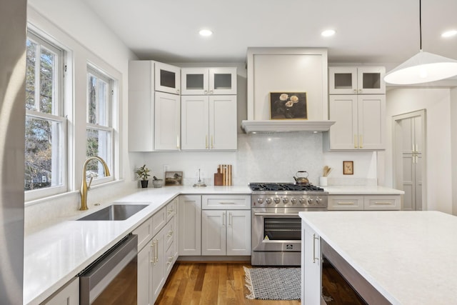 kitchen with appliances with stainless steel finishes, sink, pendant lighting, and white cabinets