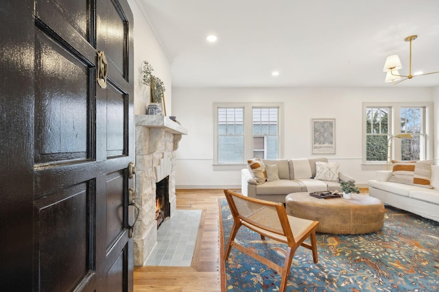 living room with a healthy amount of sunlight, a fireplace, a chandelier, and light hardwood / wood-style flooring