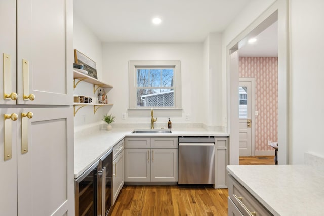 kitchen with sink, gray cabinetry, stainless steel dishwasher, beverage cooler, and light hardwood / wood-style floors