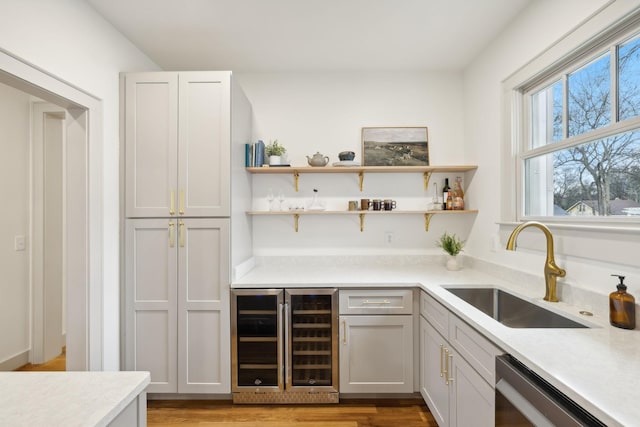 kitchen featuring stainless steel dishwasher, beverage cooler, sink, and light wood-type flooring